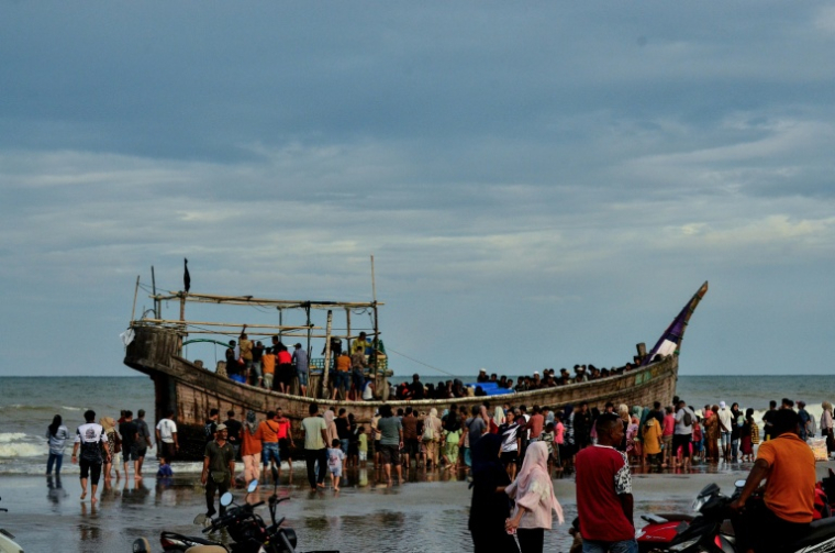 Des personnes rassemblées autour d'un bateau transportant des réfugiés rohingya, après que les autorités ont empêché les réfugiés de débarquer, sur la plage de Leuge dans la province d'Aceh, le 29 janvier 2025 en Indonésie ( AFP / Cek MAD )