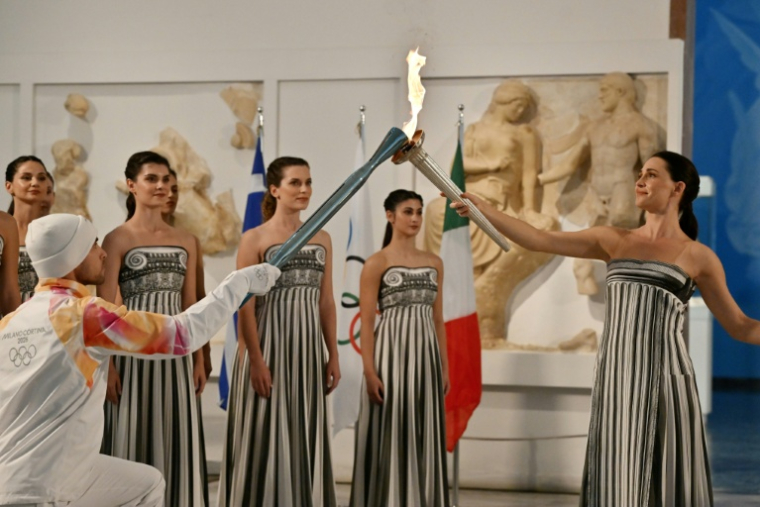 L'actrice grecque Mary Mina transmet la flamme olympique au premier relayeur pour les Jeux d'hiver 2026 de Milan-Cortina, le Grec Petros Gaidatzis, lors d'une cérémonie au Musée antique d'Olympie, en Grèce, le 26 novembre 2025 ( AFP / Aris MESSINIS )