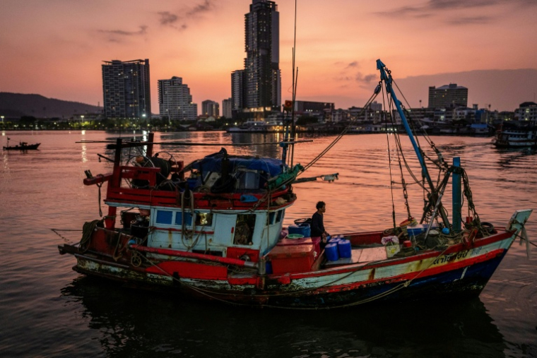Un homme se tient debout sur un bateau de pêche amarré à un quai à Si Racha, le 18 mars 2026 en Thaïlande ( AFP / Chanakarn LAOSARAKHAM )