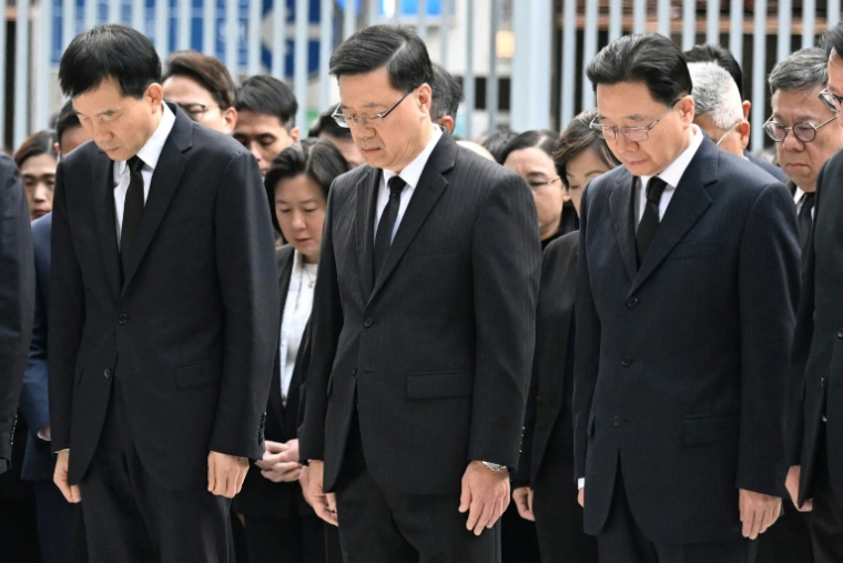 Le dirigeant de Hong Kong, John Lee (centre), observe trois minutes de silence, le 29 novembre 2025 à Hong Kong ( AFP / Peter PARKS )