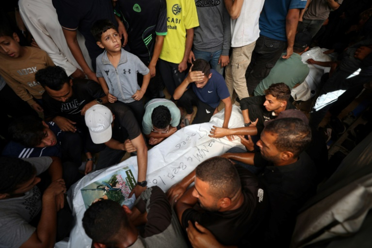 Des Palestiniens entourent à Bureij dans la bande de Gaza le corps d'un Palestinien remis par Israël dans le cadre d'un échange contre les dépouille d'otages aux mains du Hamas, le 18 octobre 2025 ( AFP / Eyad BABA )