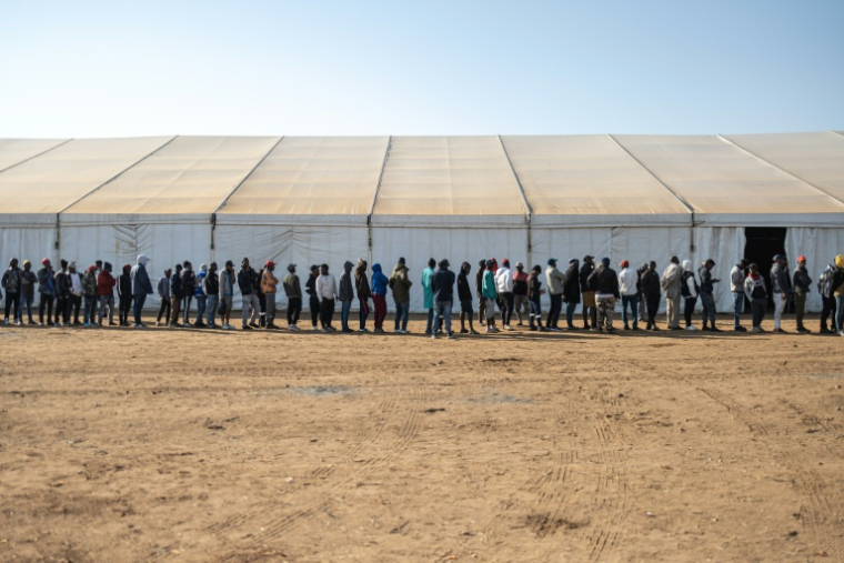 Des hommes font la queue pour être enregistrés dans le camp de transit de Musina en Afrique du Sud, le 9 juillet 2026 ( AFP / EMMANUEL CROSET )