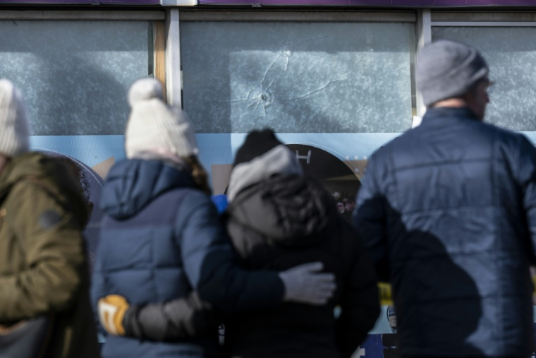 Recueillement à Minneapolis, dans le Minnesota, le 26 janvier 2026, devant des impacts de balles dans la vitrine d'un commerce sur les lieux de la mort d'Alex Pretti, décédé deux jours plus tôt ( AFP / ROBERTO SCHMIDT )