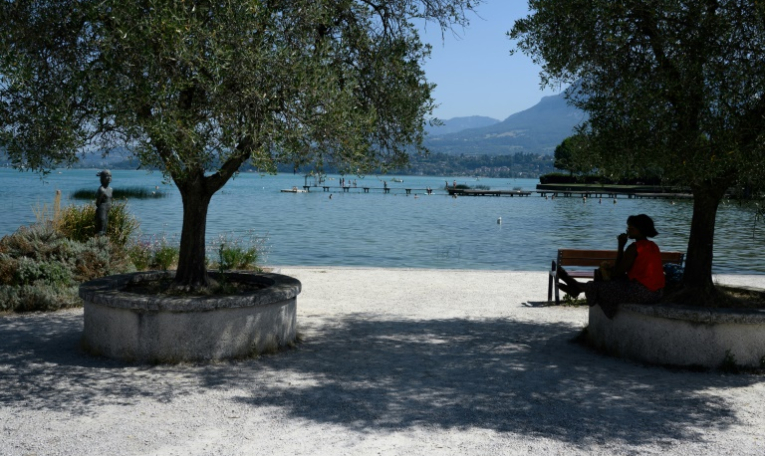 Une femme s'abrite du soleil à l'ombre d'un arbre sur une rive du lac du Bourget, au Bourget-du-Lac, en Savoie le 8 août 2025 ( AFP / JEAN-PHILIPPE KSIAZEK )