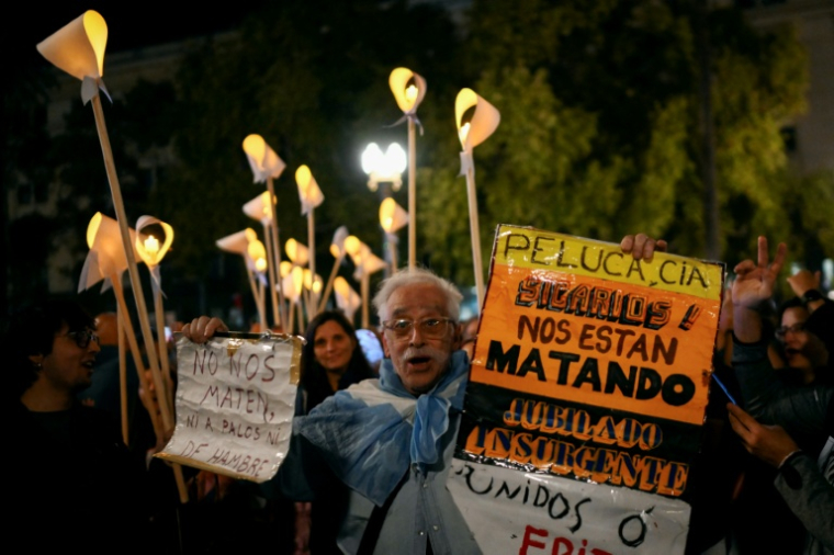 Un homme tient une pancarte tandis que des gens se rassemblent sur la Plaza de Mayo à Buenos Aires, le 23 mars 2026, pour participer à une veillée, la veille du 50e anniversaire du coup d'Etat qui a marqué le début de la dictature militaire (1976-1983) ( AFP / Luis ROBAYO )