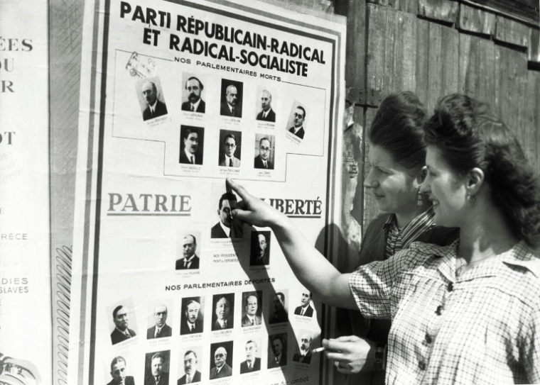 Des femmes devant une affiche électorale pour les élections municipales, avant de voter pour la première fois en France, le 29 avril 1945 à Paris ( AFP / - )