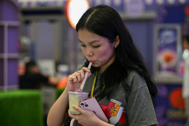 Une cliente boit une boisson à l'ube et au matcha dans un centre commercial de Quezon City, dans la métropole de Manille, le 23 septembre 2026 aux Philippines ( AFP / Jam STA ROSA )