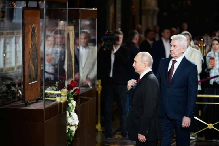 Le président russe Vladimir Poutine (C) sous les yeux d'Errol Musk (à l'arrière-plan avec une veste beige) dans la cathédrale du Christ-Sauveur de Moscou pour des célébrations de Pâques, le 11 avril 2026 ( POOL / Alexander Zemlianichenko )