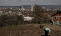 Un homme travaille dans son jardin qui surplombe une centrale thermique au charbon, près de la ville d'Obilic, au Kosovo, le 10 avril 2026 ( AFP / Armend NIMANI )