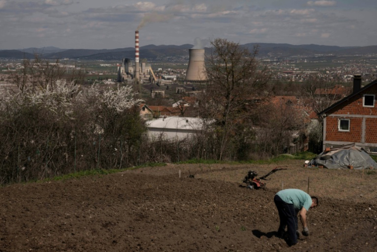 Un homme travaille dans son jardin qui surplombe une centrale thermique au charbon, près de la ville d'Obilic, au Kosovo, le 10 avril 2026 ( AFP / Armend NIMANI )