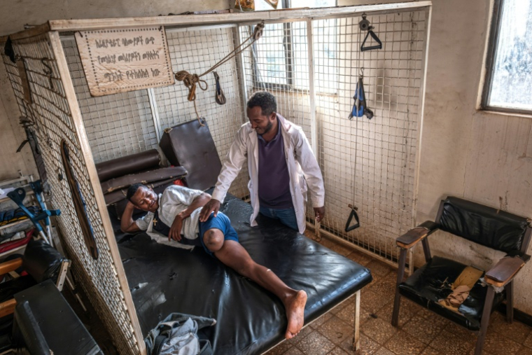 Belete Melke (g), 25 ans, blessée à la jambe par des tirs croisés, effectue des exercices de physiothérapie avec le technicien orthopédiste Bashawgize Getie au centre de rééducation physique de Bahir Dar, le 8 décembre 2025 ( AFP / Marco Simoncelli )
