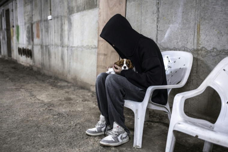 Un homme serre son chien dans ses bras dans un parking souterrain servant d'abri anti-bombes lors d'une alerte à Tel Aviv, le 12 mars 2026 en Israël ( AFP / OLYMPIA DE MAISMONT )