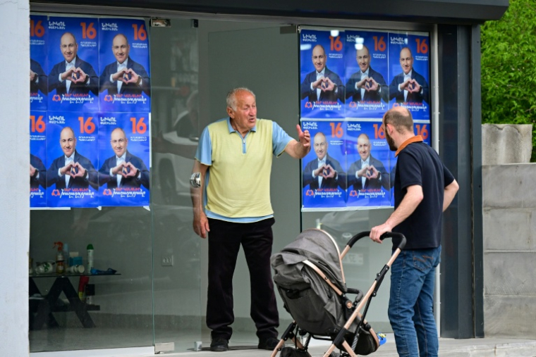 Des hommes se tiennent près d'affiches électorales et d'une banderole du parti "Contrat civil" du Premier ministre arménien Nikol Pachinian à Erevan, le 4 juin 2026, à quelques jours des élections législatives. ( AFP / Karen MINASYAN )
