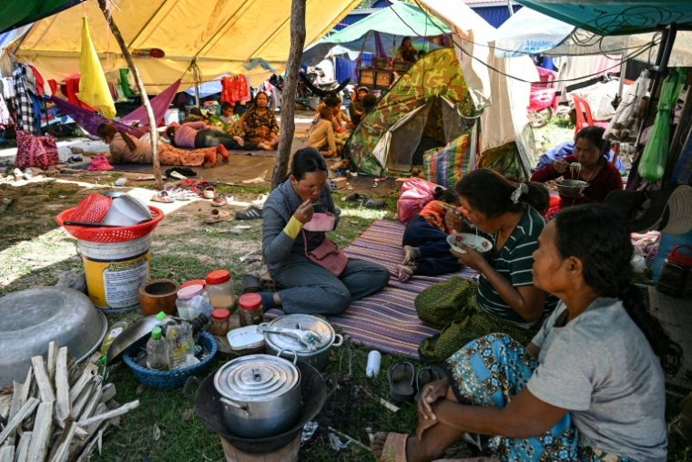 Des habitants déjeunent à l'extérieur d'un temple après avoir été évacués suite à des affrontements le long de la frontière entre le Cambodge et la Thaïlande, dans la province de Siem Reap au Cambodge, le 9 décembre 2025 ( AFP / TANG CHHIN SOTHY )