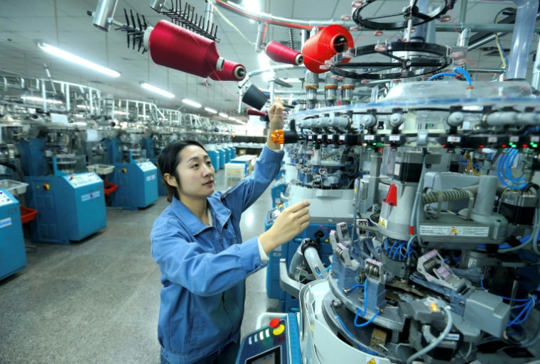 Un ouvrier utilise une machine dans une usine textile à Qingdao, dans la province du Shandong, dans l'est de la Chine, le 15 décembre 2025 ( AFP / - )