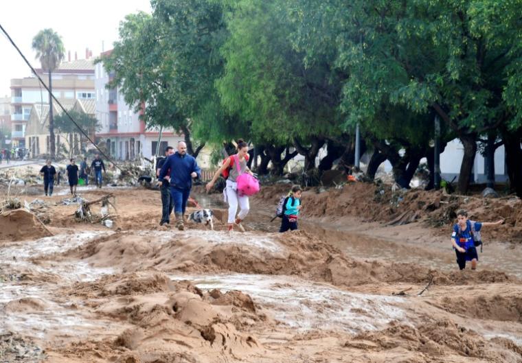 Une famille marche dans une rue envahie par la boue après les inondations qui ont touché la région de Valence, le 30 octobre 2024 à Picanya, en Espagne ( AFP / Jose Jordan )