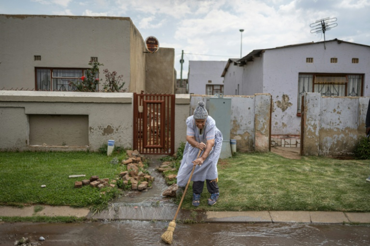 Morongoe Lephato tente d'évacuer des eaux usées devant sa maison du township de Katlehong, près de Johannesburg, le 5 octobre 2026. ( AFP / EMMANUEL CROSET )