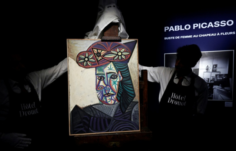 Des employés de l'Hôtel Drouot dévoilent un tableau de Pablo Picasso intitulé "Buste de femme au chapeau à fleurs" représentant Dora Maar, le 18 septembre 2025 à l'Hôtel Drouot à Paris avant la mise aux enchères de l'oeuvre le 24 octobre 2025 ( AFP / STEPHANE DE SAKUTIN )