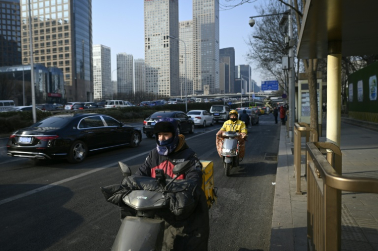 Des livreurs de repas conduisent des scooters électriques à Pékin, le 16 janvier 2024 ( AFP / WANG Zhao )