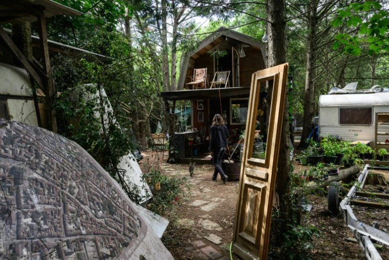 Une femme devant une cabane du "Quartier libre des Lentillères", une ZAD urbaine à Dijon, le 3 août 2025 en Côte d'Or ( AFP / ARNAUD FINISTRE )