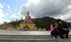 Un couple assis regarde l'écran d'un téléphone portable à côté d'une statue de Bouddha à Thimphou, la capitale du Bouthan, le  25 août 2018 ( AFP / ARUN SANKAR )