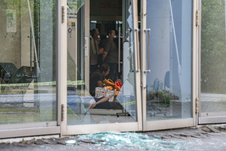 Des éclats de verre jonchent le sol tandis que des évacués se reposent dans un centre d'hébergement aménagé à l'hôtel de ville d'Uki, dans la préfecture de Kumamoto, le 29 juillet 2026, au lendemain du séisme qui a frappé le sud-ouest du Japon ( AFP / Philip FONG )