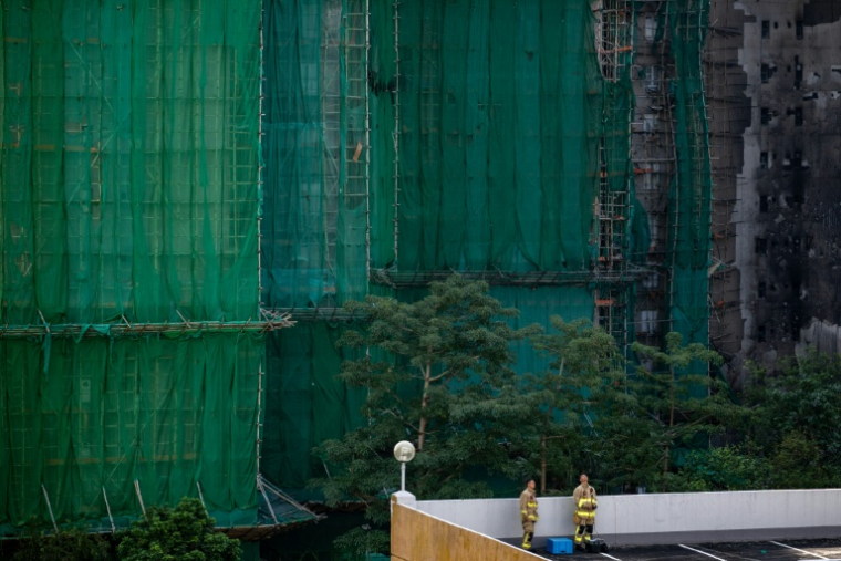 Des pompiers prennent une pause près du complexe résidentiel Wang Fuk Court à Hong Kong, ravagé par un incendie, le 28 novembre 2025 ( AFP / Philip FONG )