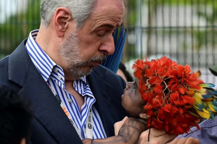 Le président de la COP30, Andre Correa do Lago, tient un bébé indigène de la communauté munduruku lors d'une manifestation à l'entrée de la COP30 à Belem, au Brésil, le 14 novembre 2025 ( AFP / Pablo PORCIUNCULA )