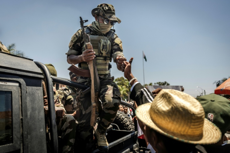 Un militaire malgache salue du poing un civil alors que des manifestants se rassemblent pour un meeting de la société civile devant l'hôtel de ville d'Antananarivo, le 13 octobre 2025 ( AFP / Luis TATO )