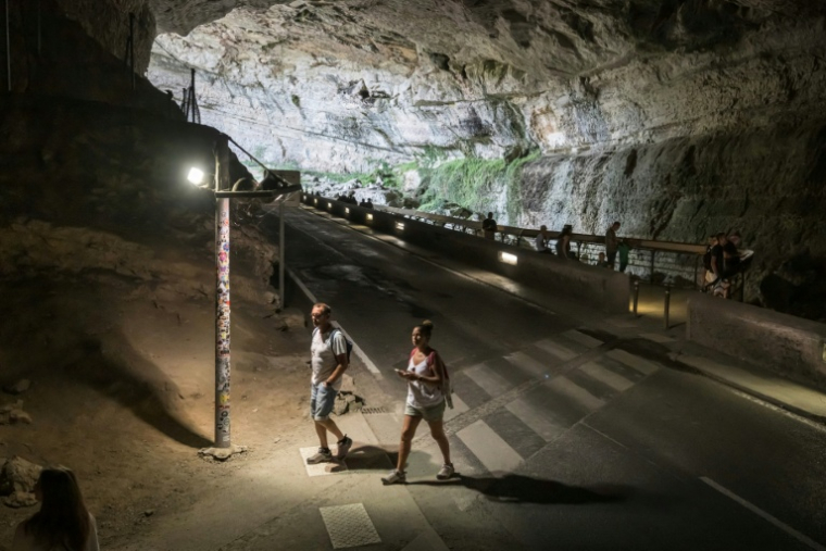 Des personnes marchent dans la grotte du Mas d'Azil, en Ariège, le 5 août 2026 ( AFP / Ed JONES )