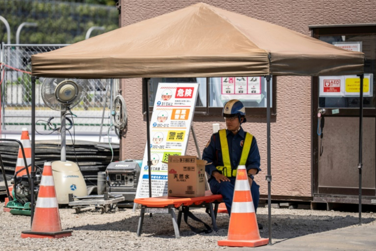 Un ouvrier fait une pause à l'ombre lors d'une chaude journée à Tokyo, le 27 août 2025 ( AFP / Yuichi YAMAZAKI )