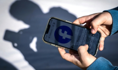 Un adolescent consulte Facebook sur son téléphone portable à Gosford, le 24 octobre 2025 en Australie ( AFP / David GRAY )