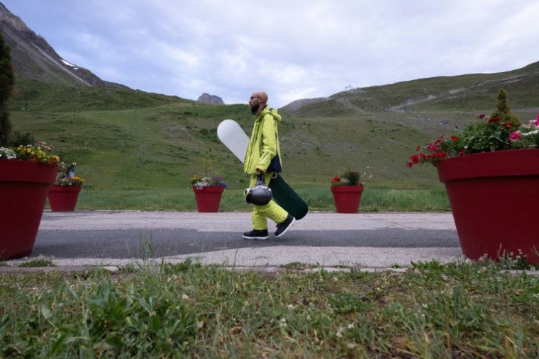 Un snowboardeur se dirige vers le funiculaire de la Grande Motte , le 11 juillet 2026 à Tignes, en Savoie ( AFP / Alex MARTIN )
