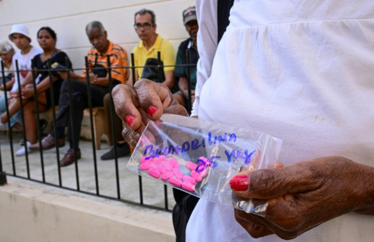 Une Cubaine montre les médicaments qu'elle vient de recevoir gratuitement grâce à un programme social mis en oeuvre à l'église catholique Santa Cruz de Jérusalem, à La Havane, le 14 avril 2026 ( AFP / YAMIL LAGE )
