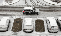 Une voiture passe devant des voitures couvertes de neige garées sur un parking après des chutes de neige à Rzeszow