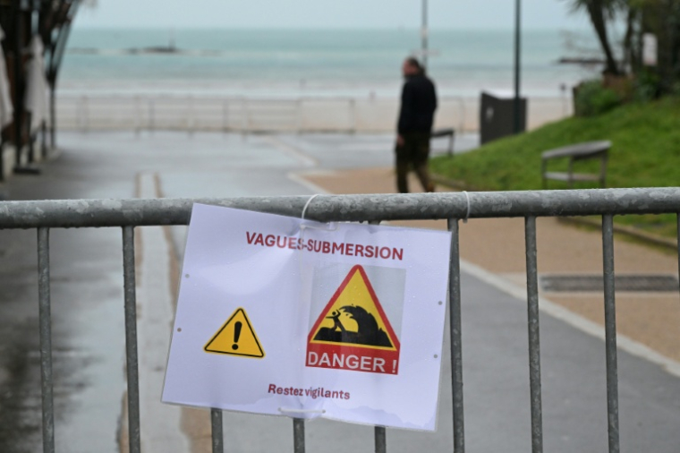 Des barrières avec une affiche de mise en garde pour les risques de vague-submersion devant l'accès à la plage de Dinard, en Ille-et-Vilaine, le 8 janvier 2026 ( AFP / Damien MEYER )