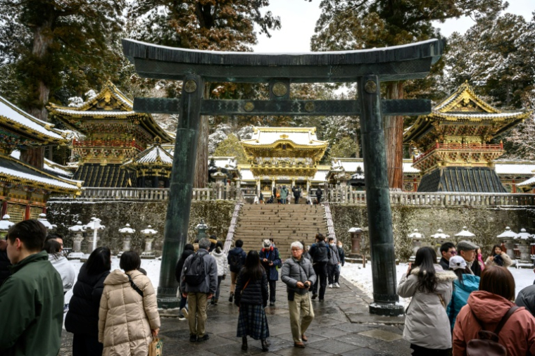 Des touristes visitent le sanctuaire Toshogu enneigé, un site touristique inscrit au patrimoine mondial de l'Unesco, le 10 février 2025 à Nikko, au Japon ( AFP / Mladen ANTONOV )