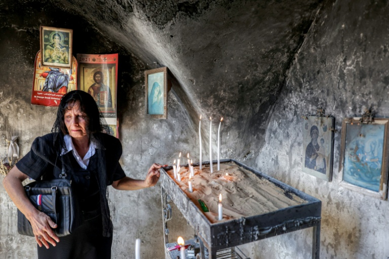 Une chrétienne allume une bougie dans l'église Saint-Georges du Ve siècle dans le village chrétien palestinien de Taybeh, au nord-est de Ramallah en Cisjordanie occupée, le 14 juillet 2025 ( AFP / Zain JAAFAR )