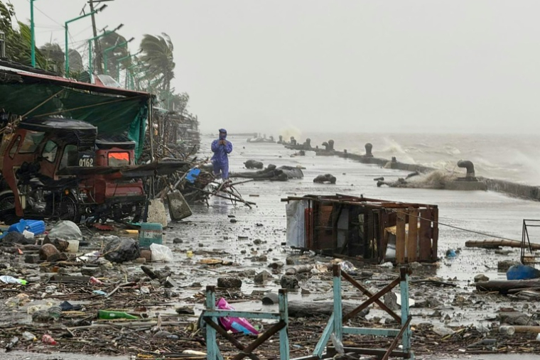 Un homme se tient à côté de débris près du bord de mer, le 22 septembre 2025 à Aparri aux Philippines ( AFP / John Dimain )