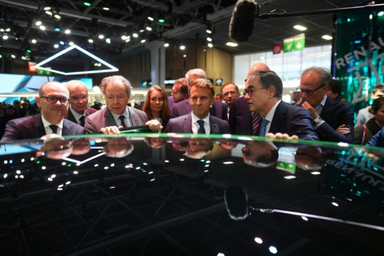 Emmanuel Macron, entouré de Luc Chatel, président de la Plateforme automobile (à gauche), et de François Provost, directeur général du groupe Renault, au Mondial de l’Auto à Paris, le 12 octobre 2026 ( POOL / Thibault Camus )
