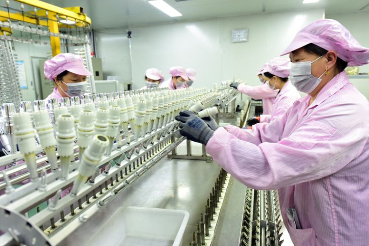 Workers work on a production line manufacturing bottle caps for export at a factory of a packaging company in Lianyungang
