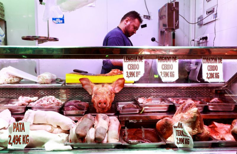 Un boucher manipule des morceaux de porc sur un étal de marché à Madrid