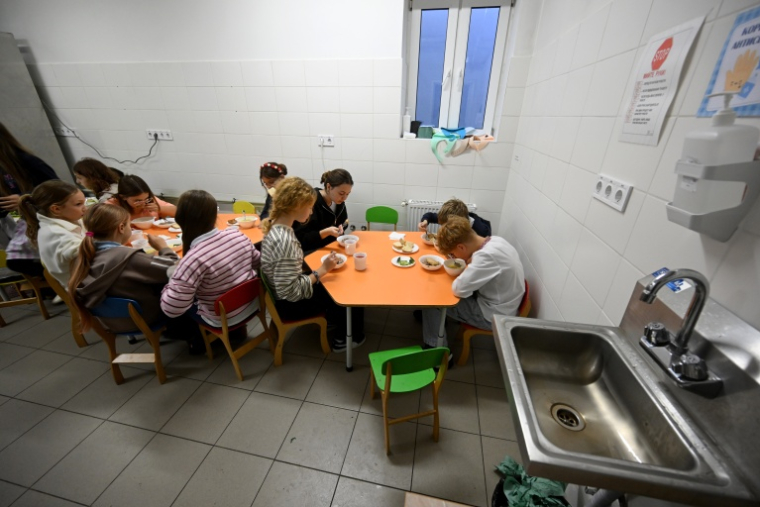 Des écoliers déjeunent dans la cantine d'un abri au sous-sol de leur établissement scolaire pendant une alerte aérienne dans la banlieue de Kiev, le 20 octobre 2026 ( AFP / Sergei SUPINSKY )