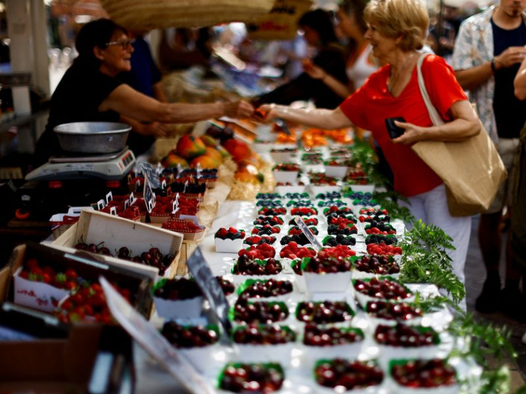 Des consommateurs achètent des fruits sur un marché local à Nice.