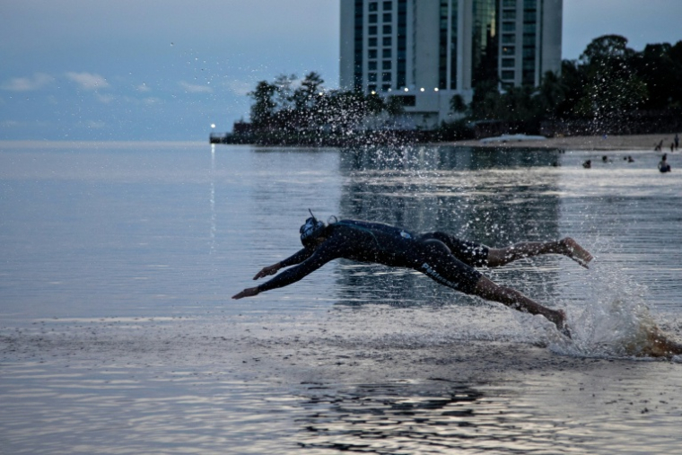 Wilber Honorio Munoz plonge dans l'eau du Rio Negro, affluent de l'Amazone, le 18 mai 2026, à Manaus  ( AFP / MICHAEL DANTAS )