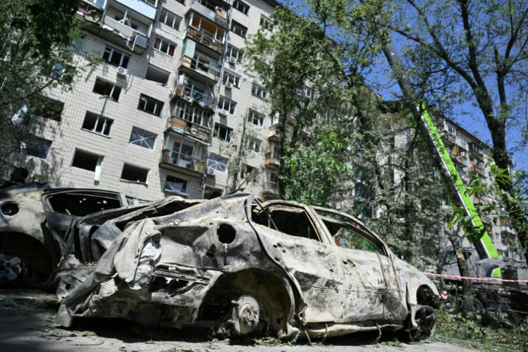Des épaves de voitures devant un immeuble résidentiel endommagé par une frappe de missile russe la veille, le 18 juin 2025 à Kiev, en Ukraine ( AFP / Genya SAVILOV )