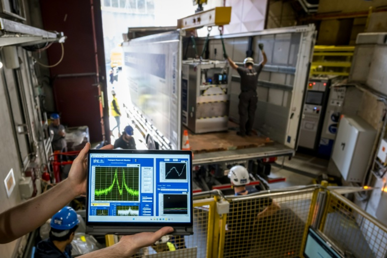 Un dispositif cryogénique portable, rempli d'un nuage de 92 antiprotons, est transféré sur un camion, lors d'un essai réussi du premier système de transport d'antimatière au monde par la route, sur le campus du Cern, à Meyrin, près de Genève, le 24 mars 2026 en Suisse ( AFP / Fabrice COFFRINI )