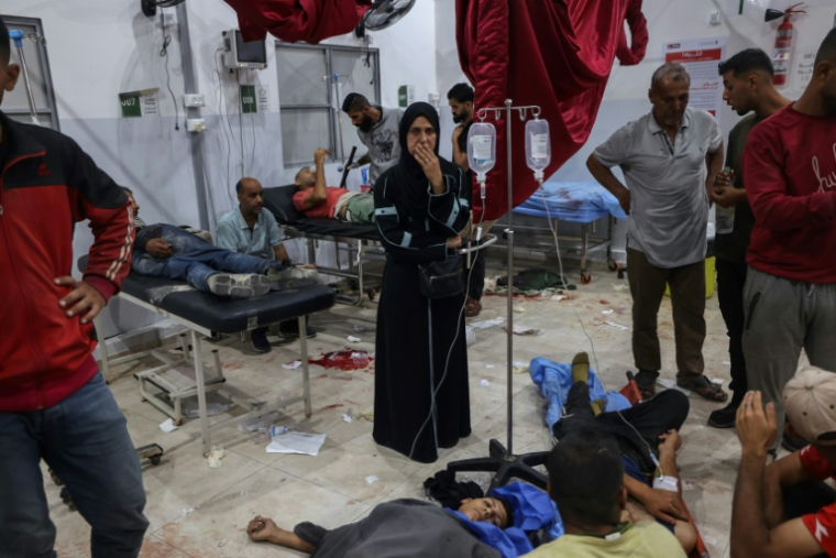 Une Palestinienne au milieu de personnes blessées par des tirs israéliens à un point de distribution d'aide alimentaire de la Fondation humanitaire de Gaza (GHF), prises en charge à l'hôpital Al-Awda du camp de réfugiés de Nousseirat, dans le centre de la bande de Gaza, le 24 juin 2025 ( AFP / Eyad BABA )