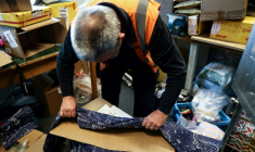 Un douanier belge ouvre un colis contenant des draps, où est cachée de la MDMA, à l'aéroport de Bruxelles le 6 avril 2023 ( AFP / Kenzo TRIBOUILLARD )