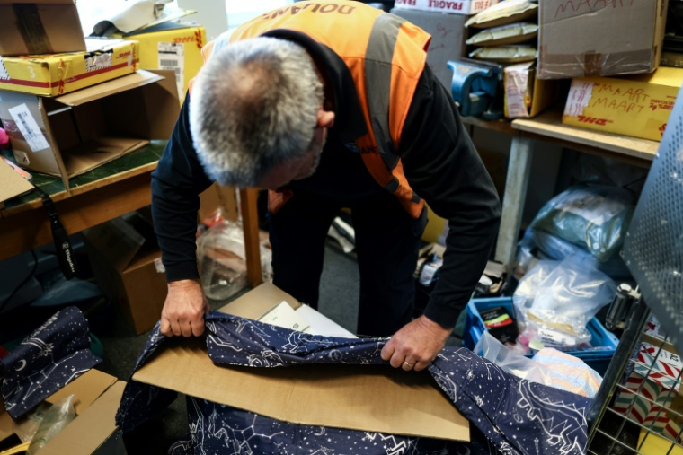 Un douanier belge ouvre un colis contenant des draps, où est cachée de la MDMA, à l'aéroport de Bruxelles le 6 avril 2023 ( AFP / Kenzo TRIBOUILLARD )